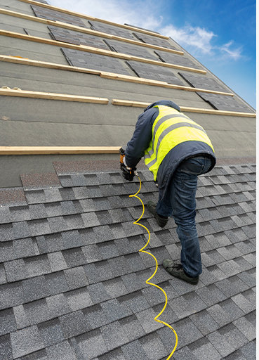 man working on roof using nailgun